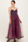 woman wearing a purple floral maternity dress with a flowy skirt and spaghetti straps, showcasing her baby bump