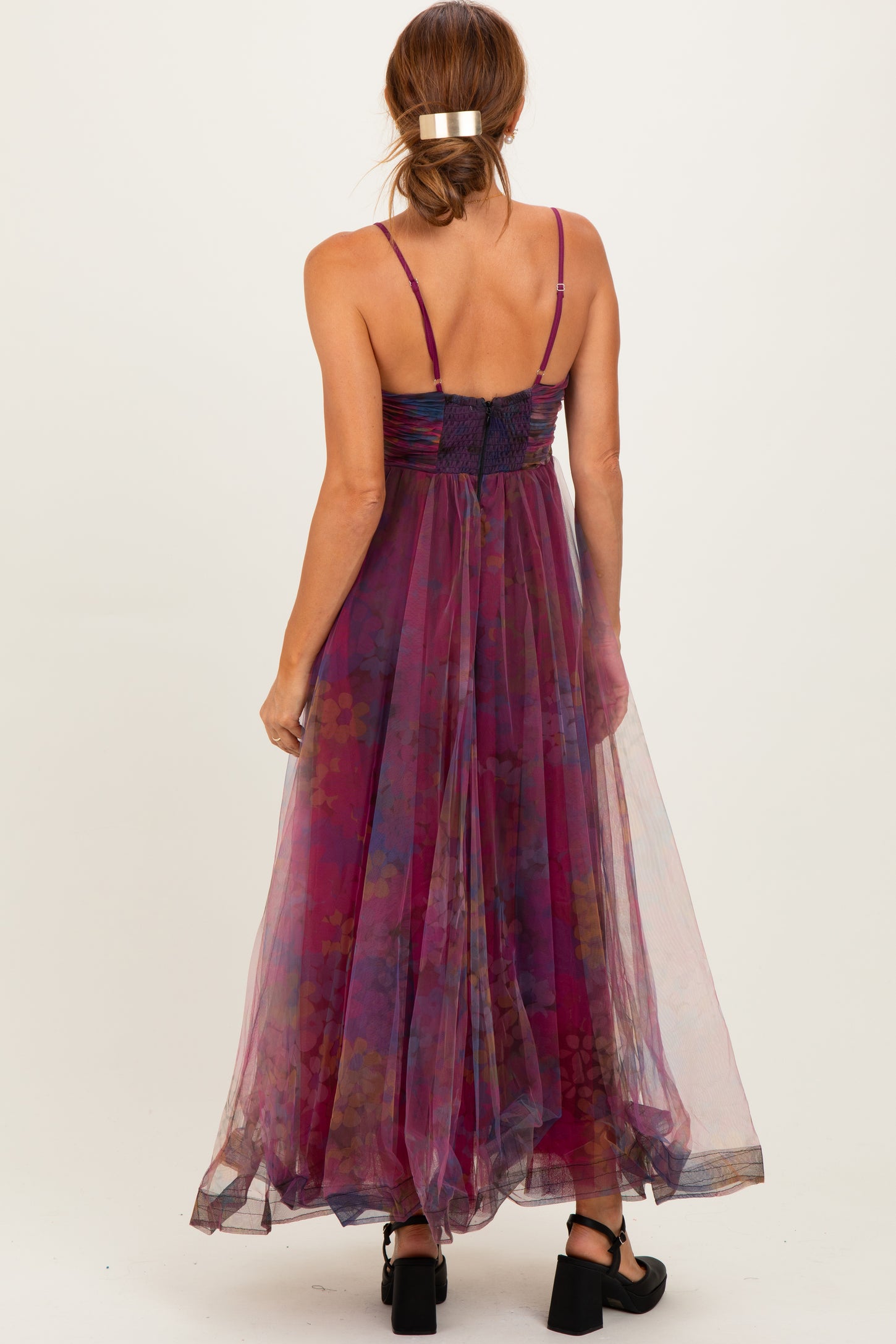 woman wearing a back view of a sleeveless purple floral maxi dress with a flowy skirt and thin straps
