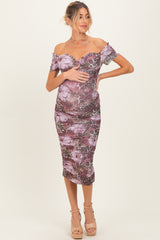 woman wearing a purple floral off-shoulder maternity dress and holding her baby bump