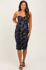woman wearing a dark blue strapless maternity dress with ruched detailing, standing and smiling