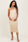 woman wearing a beige one-shoulder ribbed maternity dress and cradling her baby bump
