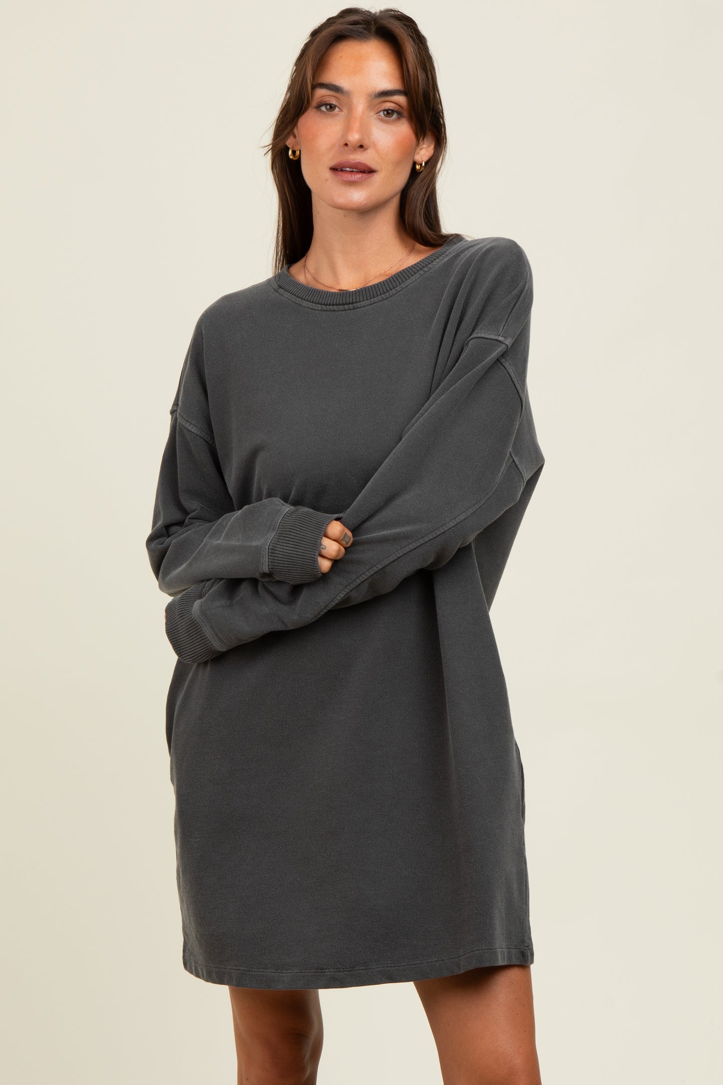 woman wearing a charcoal gray oversized sweatshirt dress with long sleeves and a relaxed fit