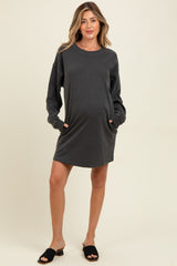 woman wearing a dark gray long sleeve maternity dress with pockets and a visible baby bump