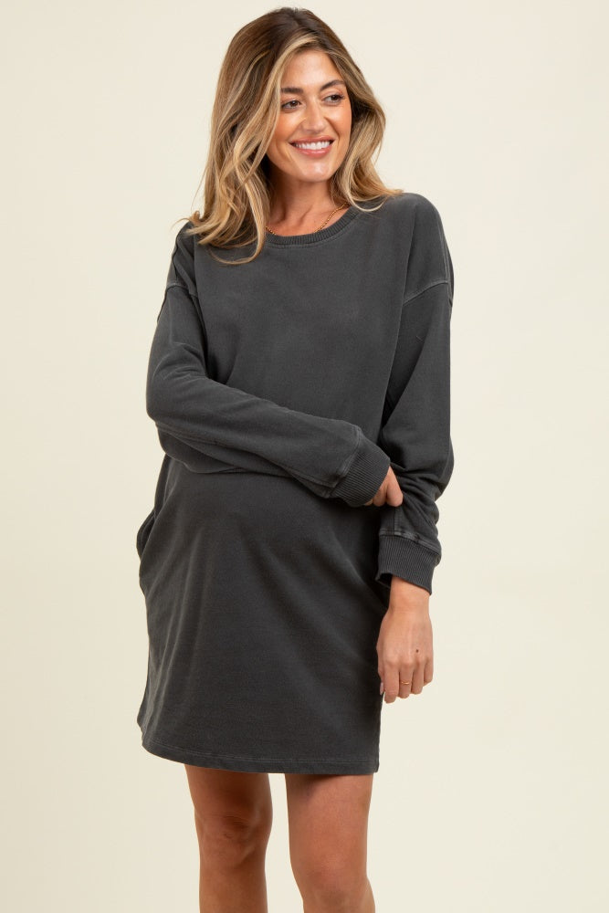 woman wearing a dark gray maternity sweatshirt dress, showing a visible baby bump
