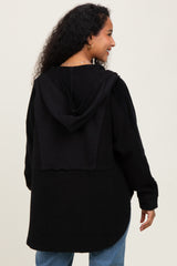 woman wearing a black maternity hoodie with a layered back detail, showing curly hair and casual style