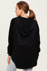 woman wearing a black oversized hoodie with a back design and a relaxed fit