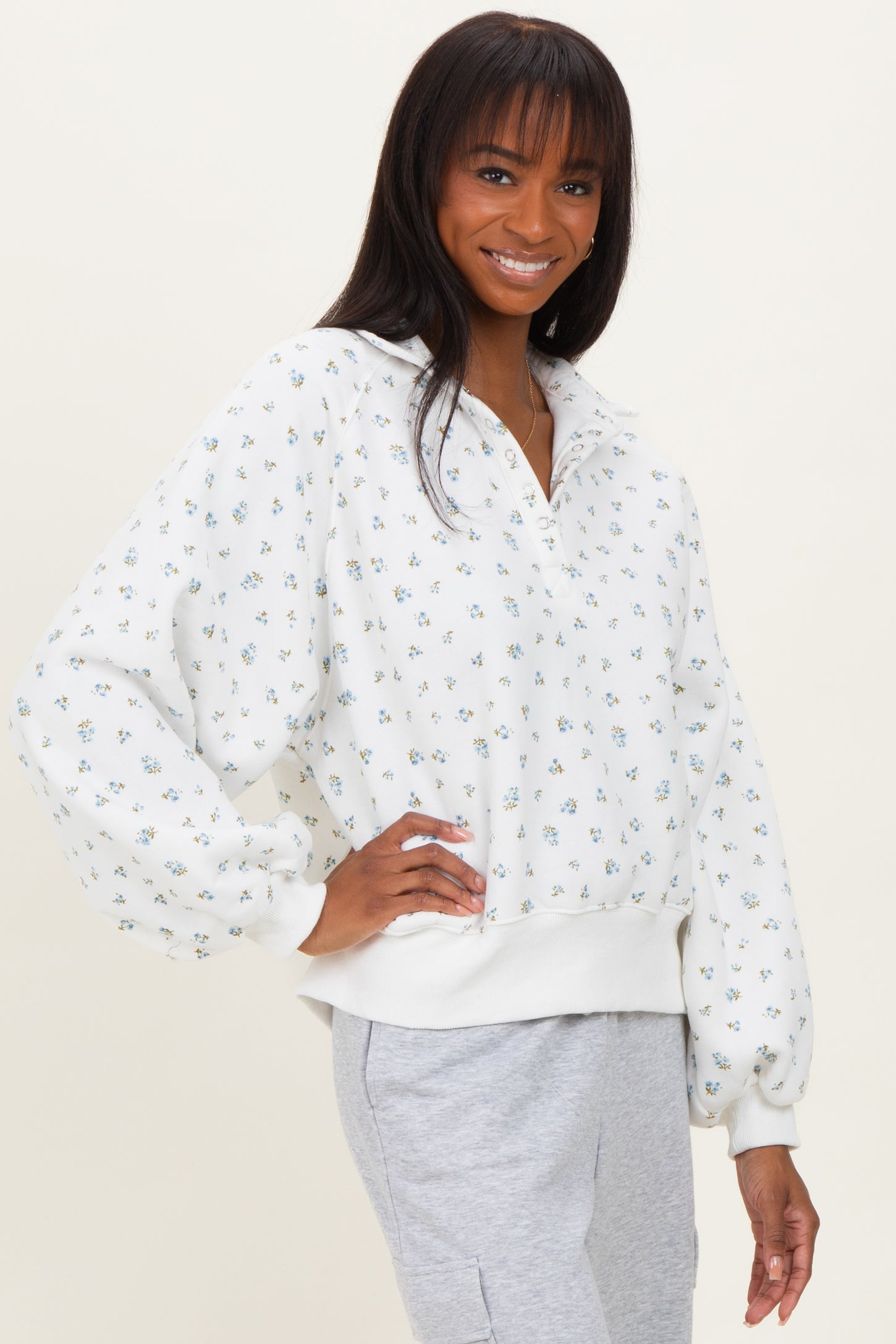 woman wearing a white floral print pullover sweatshirt with a quarter zip and relaxed fit