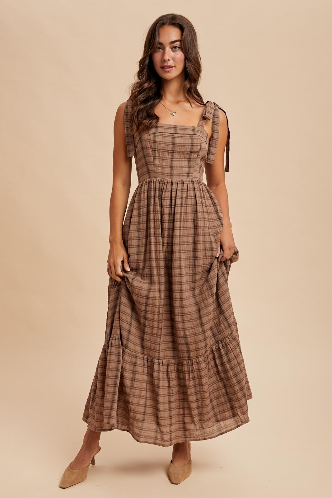 woman wearing a brown plaid maxi dress with tie straps and a tiered skirt