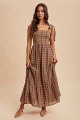 woman wearing a brown plaid maxi dress with tie straps and a tiered skirt