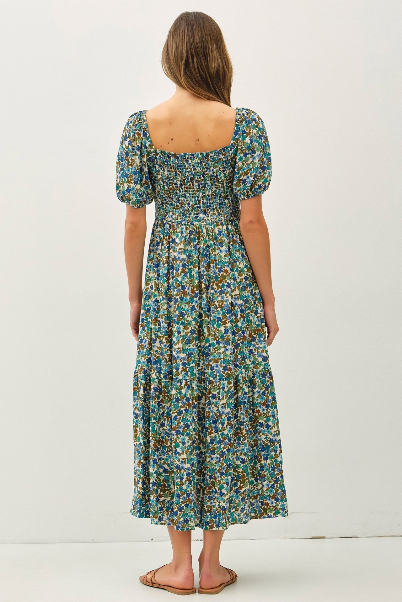 woman wearing a floral print maxi dress with puff sleeves and a smocked bodice, seen from the back