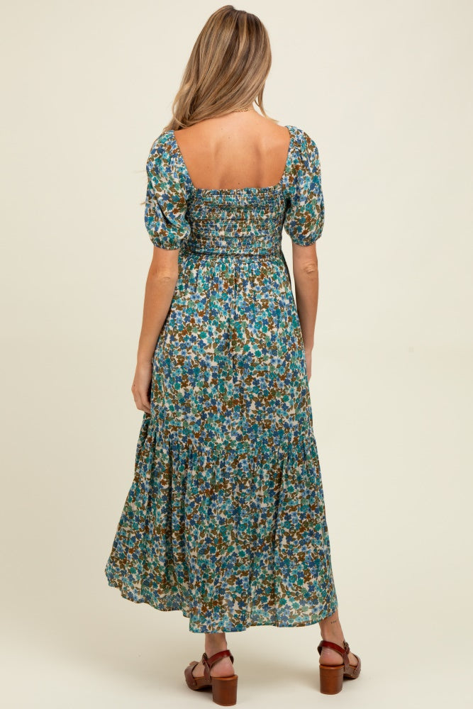 woman wearing a floral print maternity maxi dress with a smocked bodice and puffed sleeves, showing her baby bump