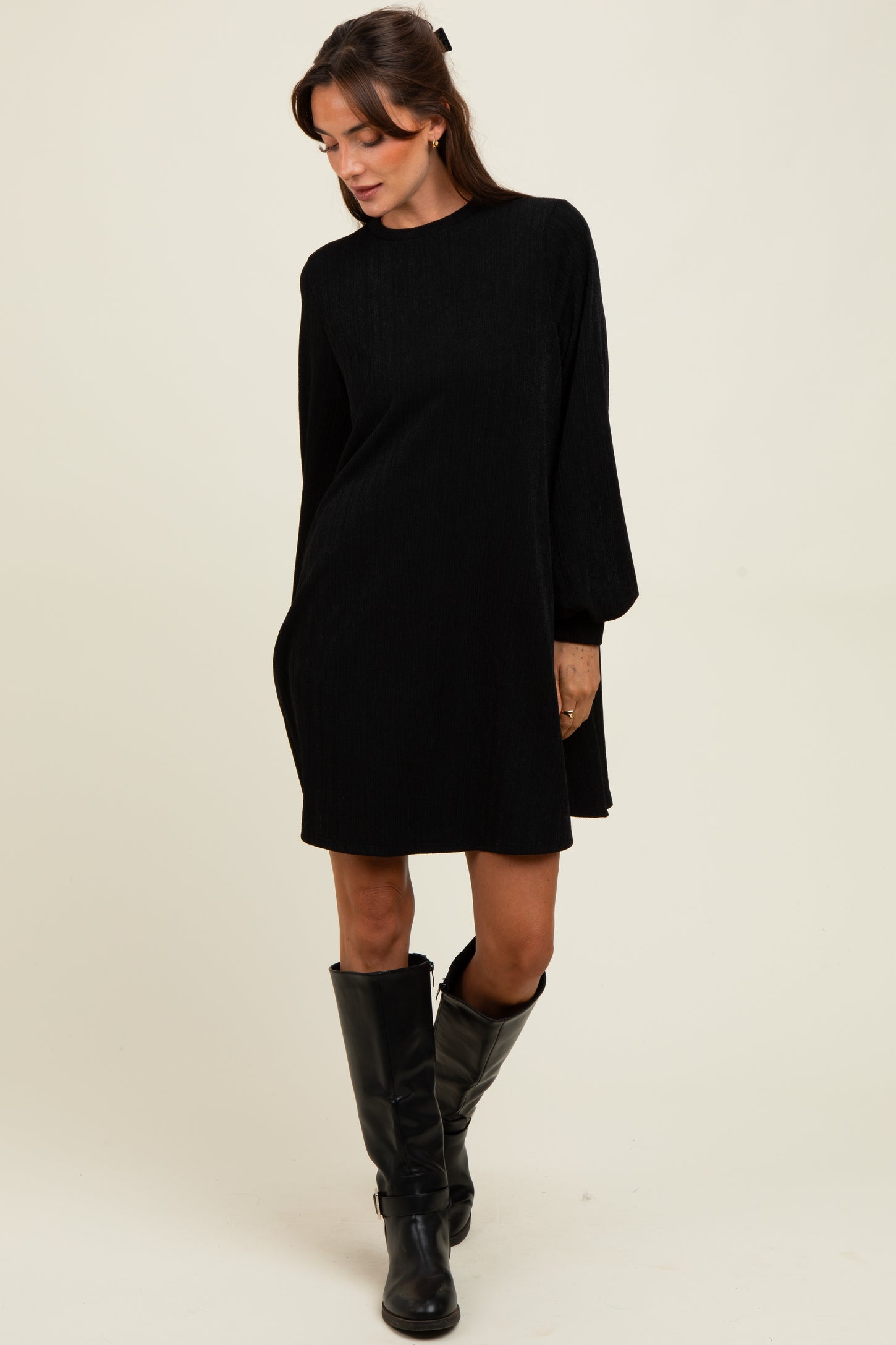 woman wearing a black long sleeve corduroy dress paired with black knee-high boots