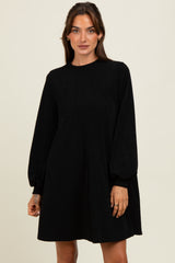 woman wearing a black corduroy mini dress with long puff sleeves and a relaxed fit