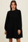 woman wearing a black corduroy mini dress with long puff sleeves and a relaxed fit