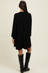 woman wearing a black long sleeve ribbed dress and knee-high black boots, viewed from the back
