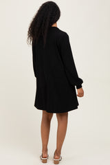 woman wearing a black ribbed maternity dress with long sleeves, shown from the back