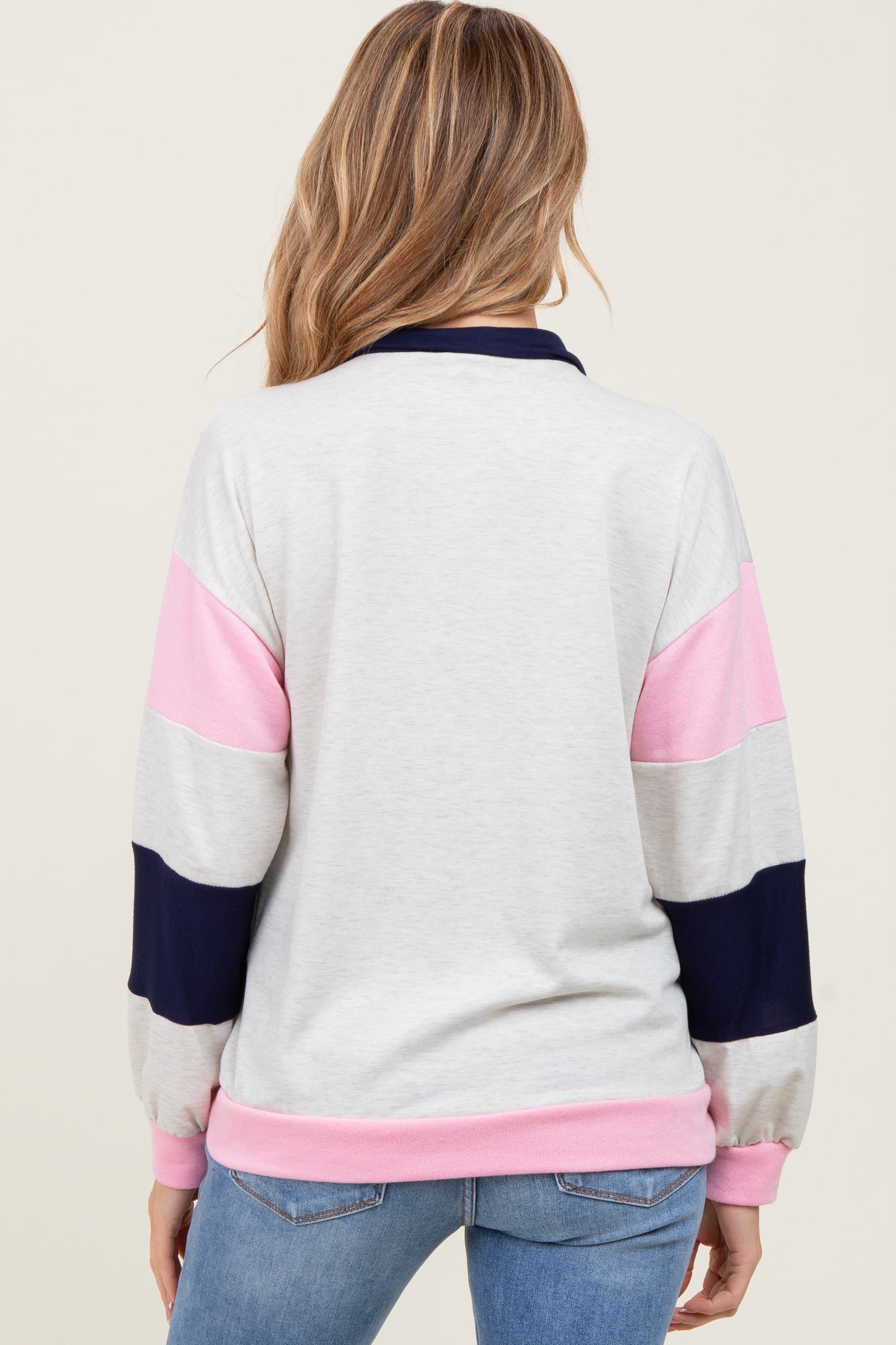 woman wearing a color-blocked gray, pink, and navy long sleeve maternity top viewed from the back