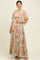 woman wearing a floral green maternity maxi dress with a deep v-neck and tie detail, holding her baby bump