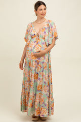 woman wearing a floral print maternity maxi dress with a deep v-neck and flowy sleeves, holding her baby bump