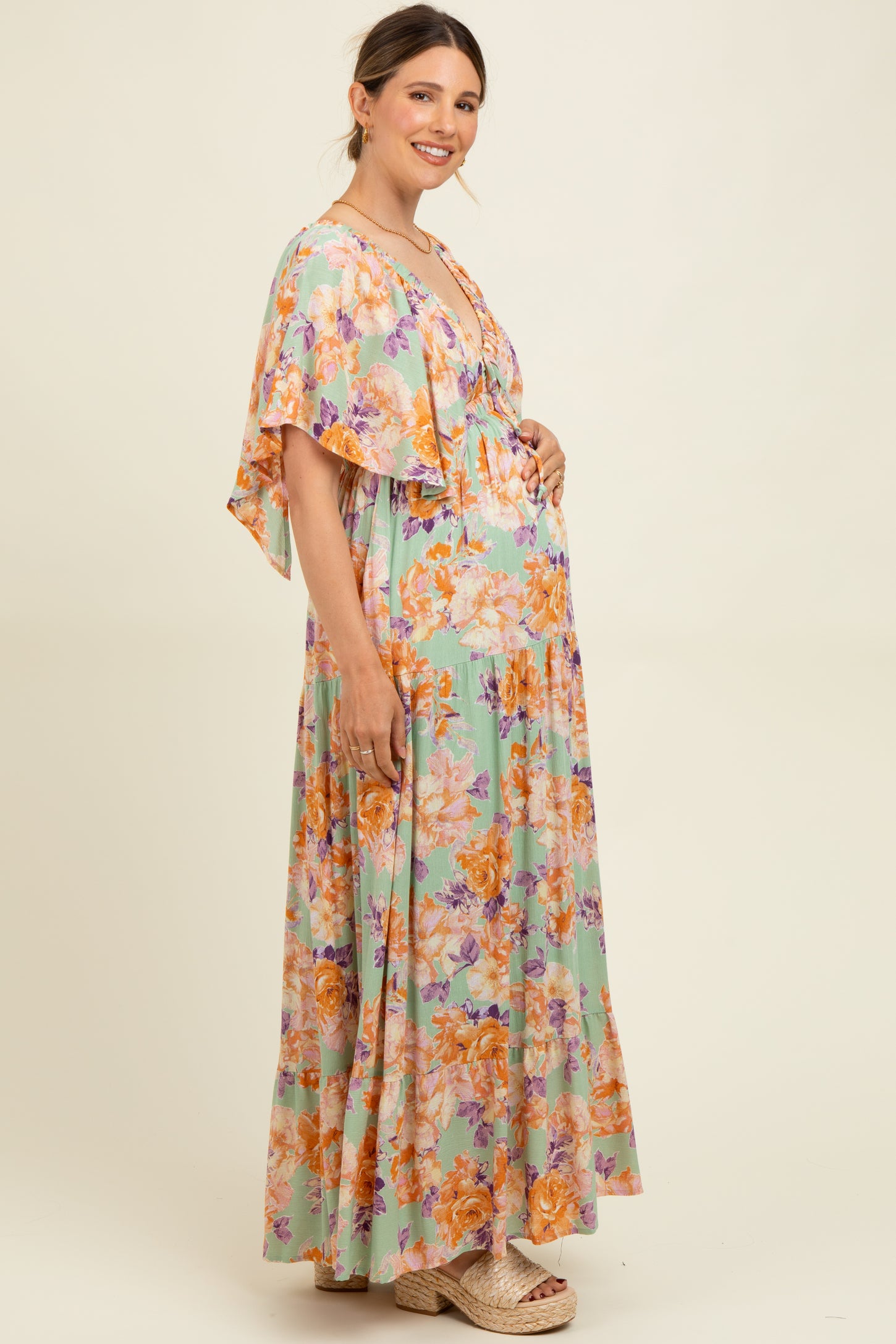 woman wearing a floral patterned maternity maxi dress with flutter sleeves and a visible baby bump