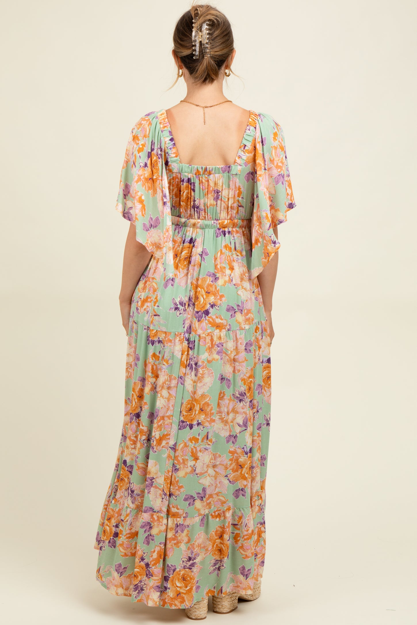 woman wearing a floral maxi maternity dress with flutter sleeves and a smocked back design