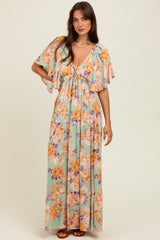 woman wearing a pastel green floral maxi dress with short flutter sleeves and tied neckline