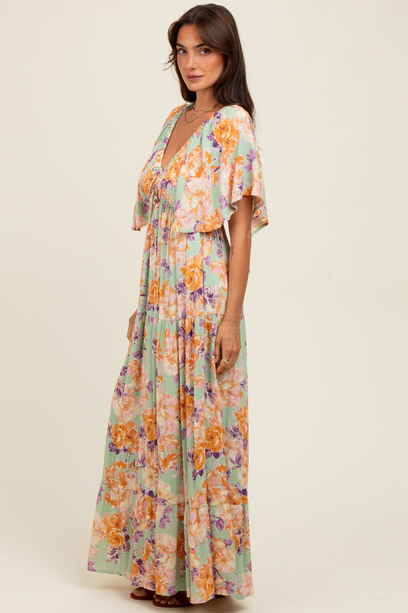 woman wearing a colorful floral maxi dress with a deep v-neck and flutter sleeves