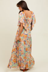 woman wearing a floral maxi dress with flutter sleeves and a smocked back in pastel colors