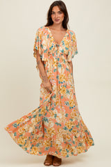 woman wearing a floral maxi dress with cap sleeves and a deep neckline, standing and smiling
