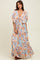 woman wearing a light blue floral maxi dress with flutter sleeves and a cinched waist