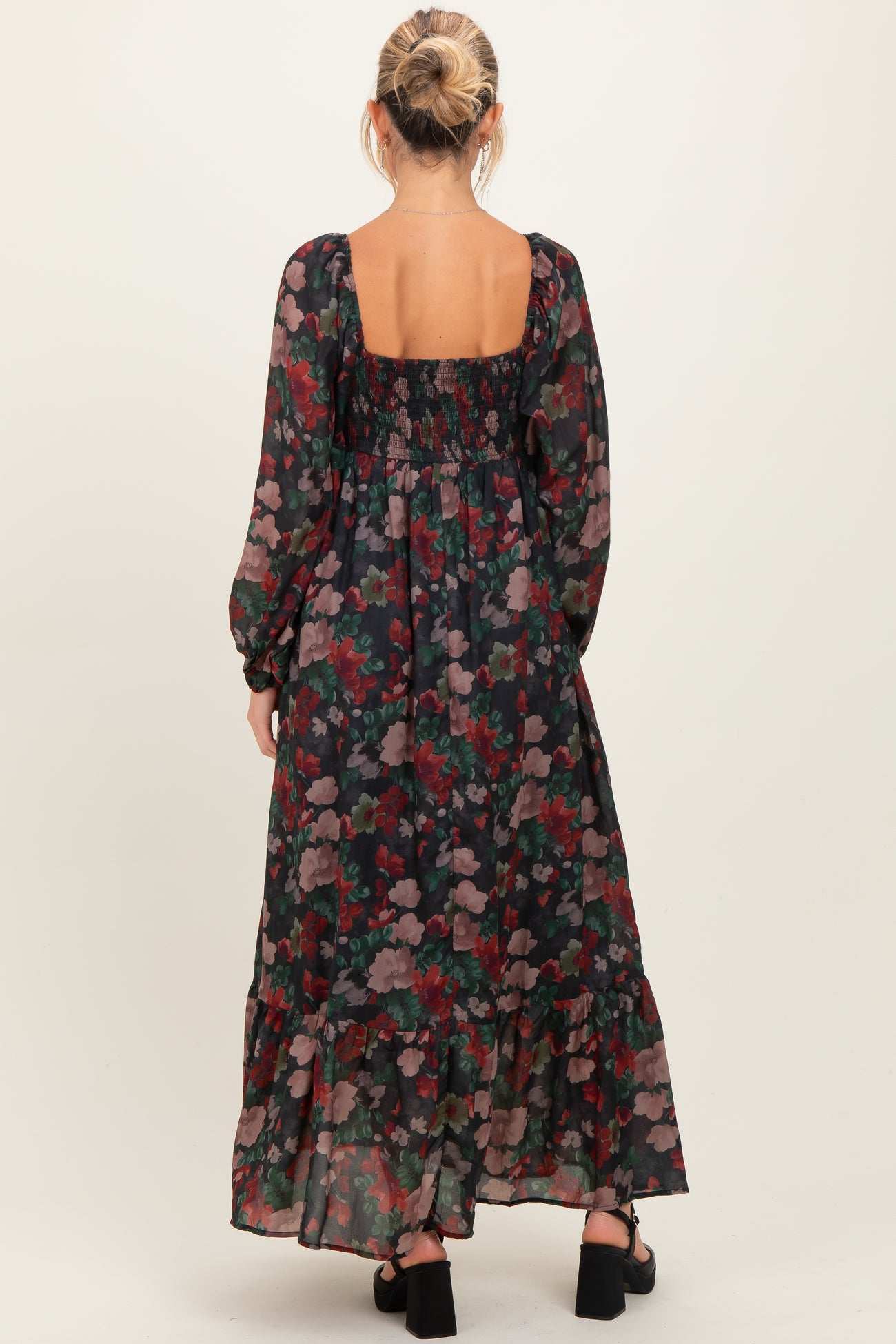 woman wearing a floral long sleeve maternity maxi dress with a square back and ruffle hemline