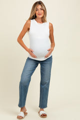 woman wearing a white sleeveless maternity top and blue jeans, holding her baby bump