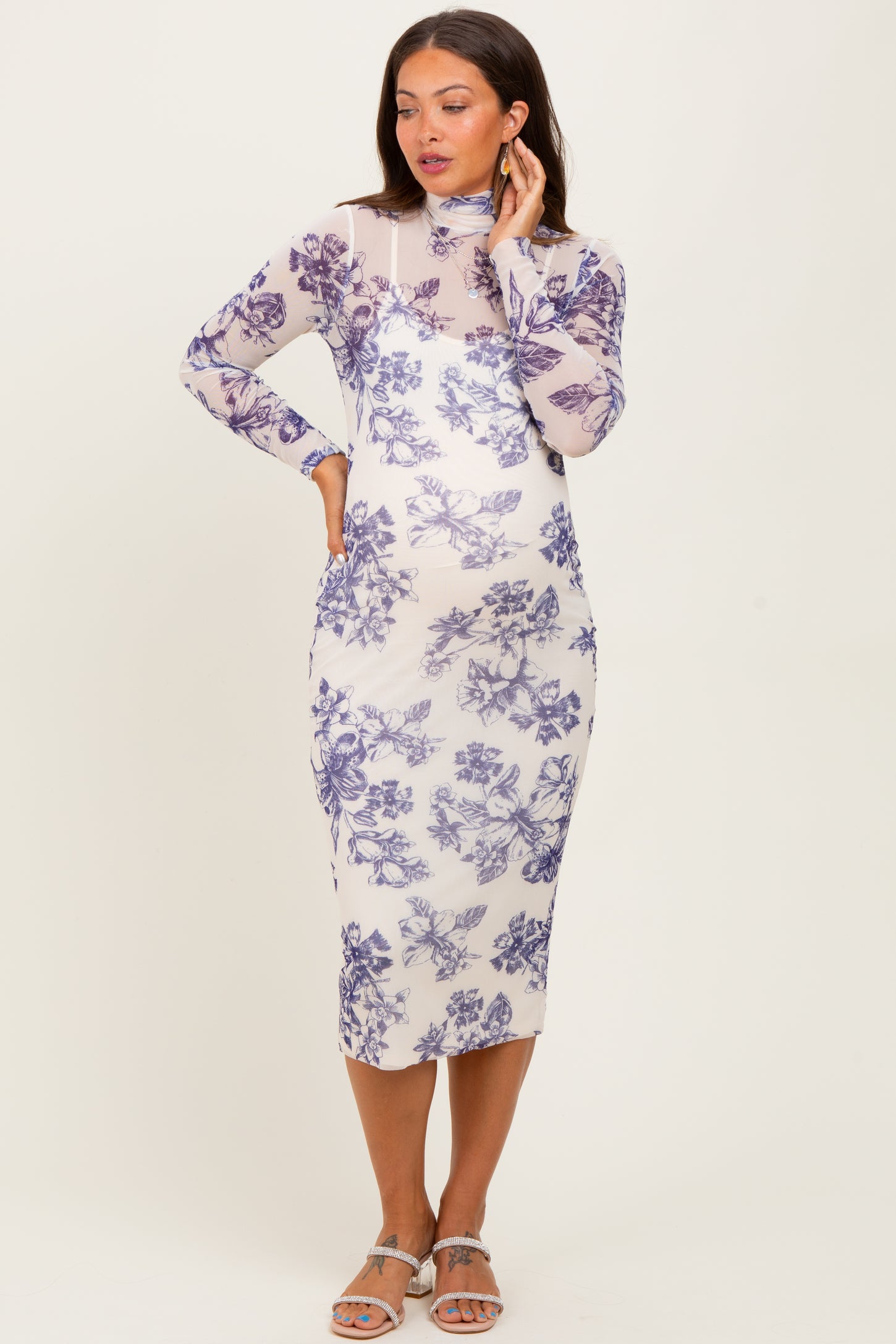 woman wearing a floral print maternity dress with long sleeves and a fitted silhouette, showing her baby bump