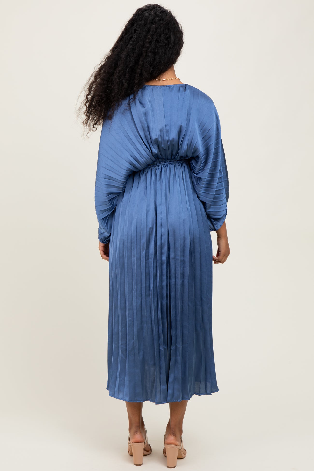 woman wearing a maternity pleated dress in light blue, showing a flowing silhouette from the back