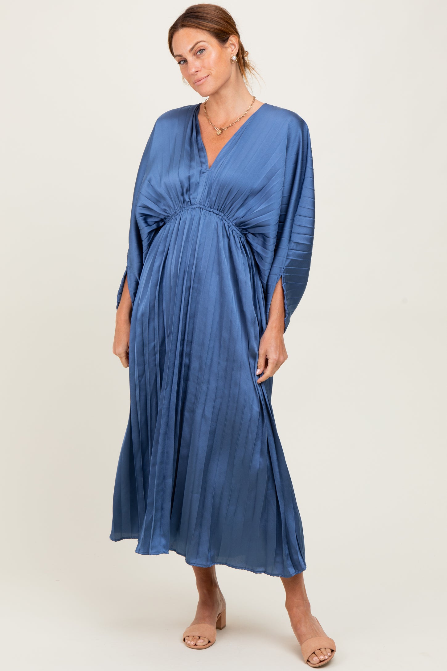 woman wearing a blue pleated maxi dress with a v-neck and loose sleeves, posing confidently