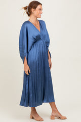 woman wearing a pleated blue maxi dress with a deep v-neck and wide sleeves