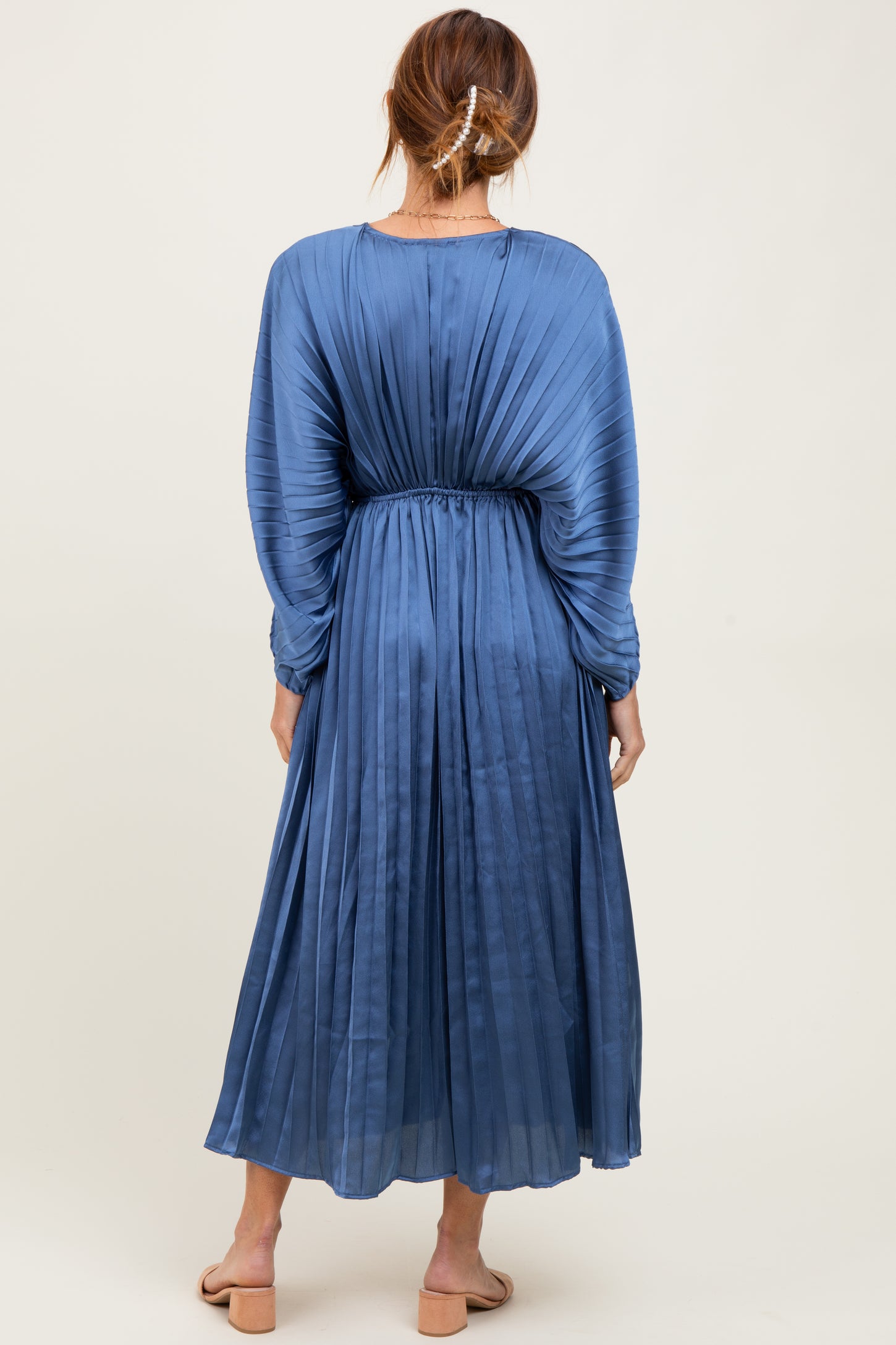woman wearing a blue pleated long sleeve maxi dress with an elastic waistband, seen from the back