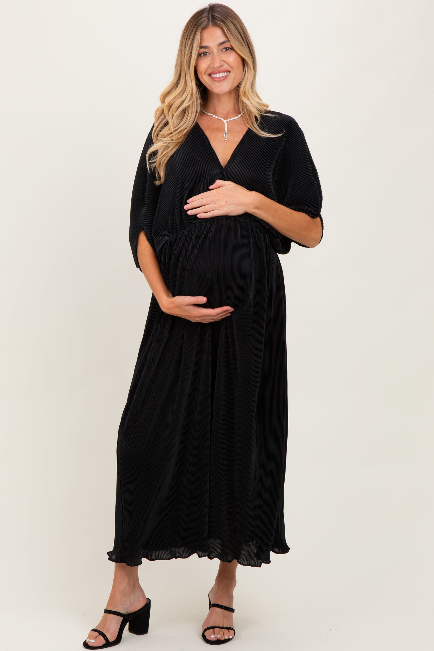 woman wearing a black ribbed maternity maxi dress and holding her baby bump