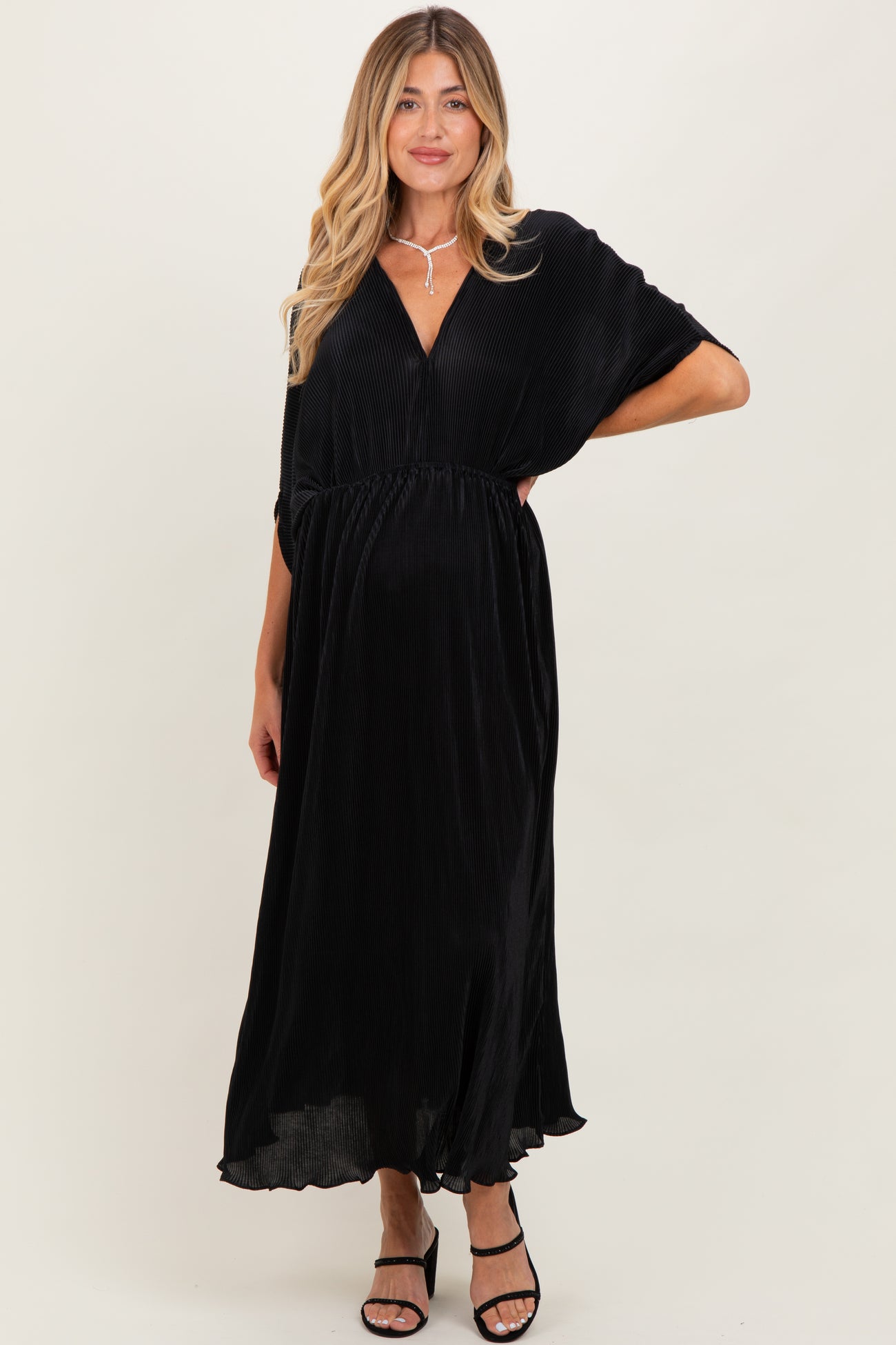 woman wearing a black maternity maxi dress with a deep v-neck and cinched waist, showcasing her baby bump