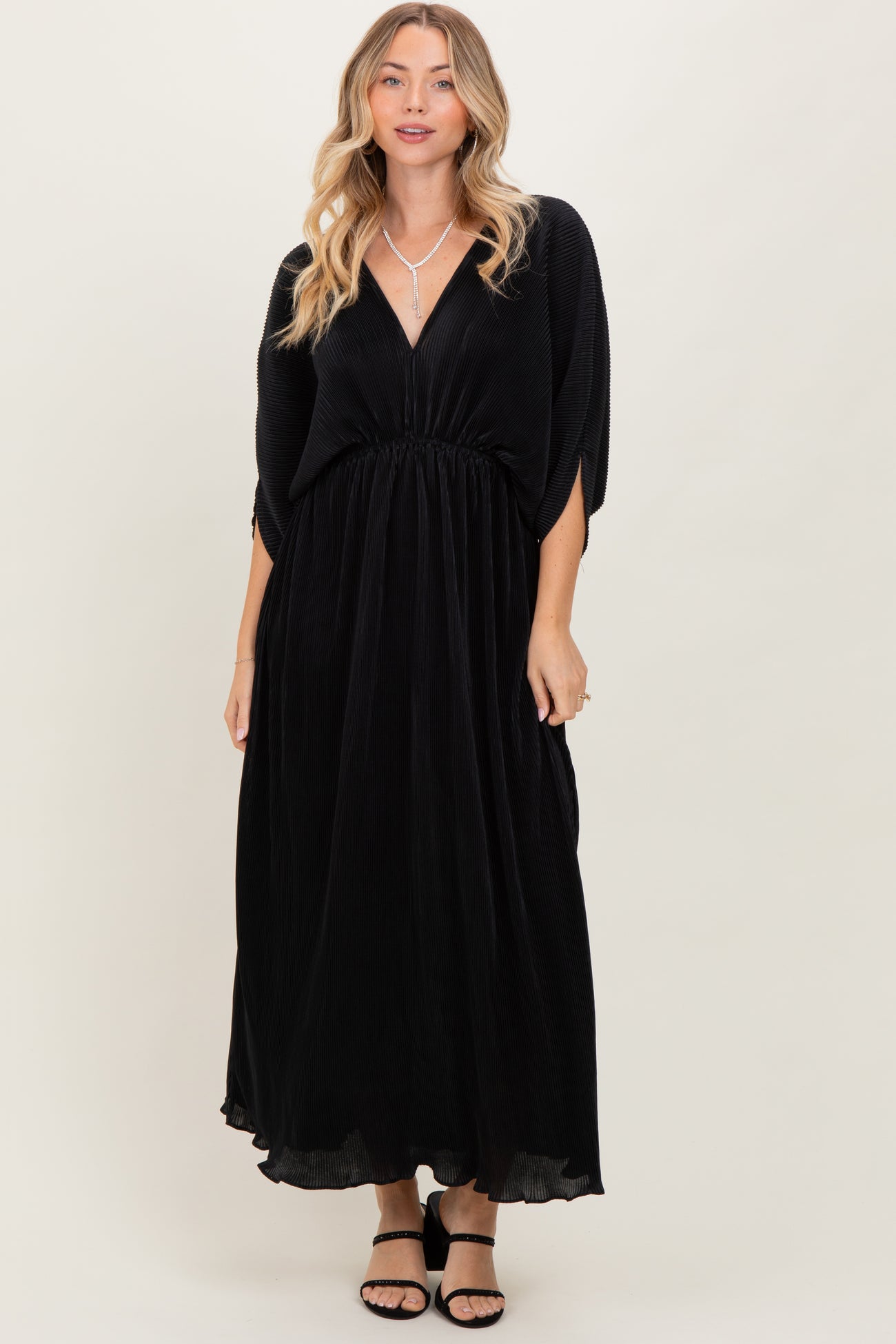 woman wearing a black maxi dress with a deep v-neck and elastic waist, styled with open-toe sandals