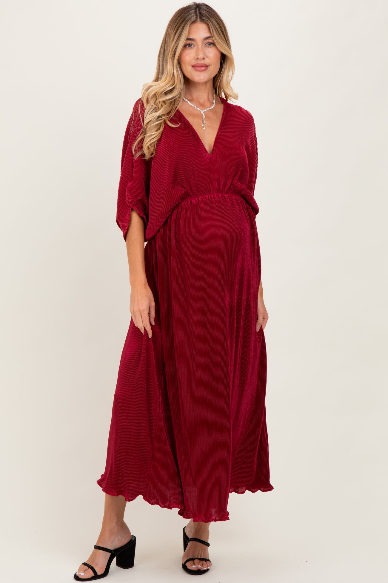 woman wearing a burgundy maternity dress with a v-neck and flowy sleeves, highlighting a baby bump