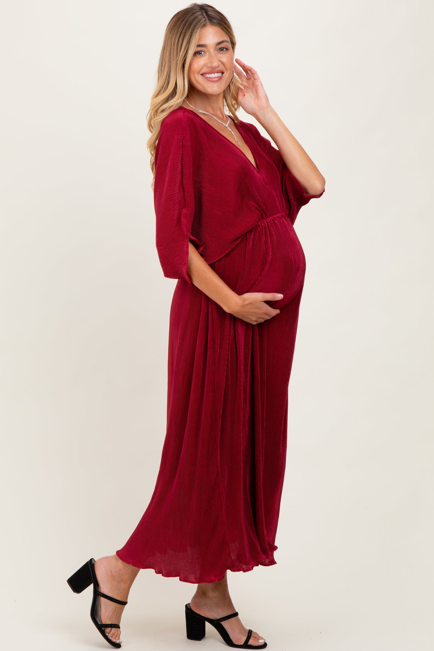 woman wearing a burgundy maternity wrap dress and holding her baby bump