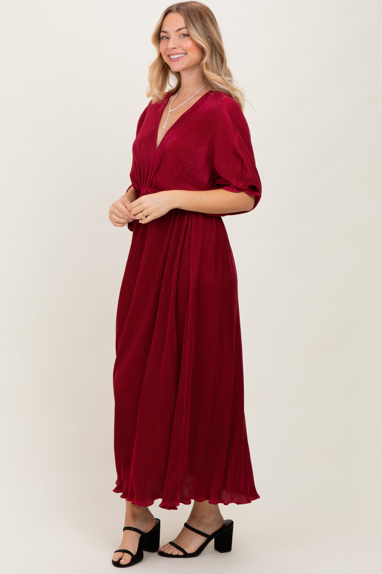 woman wearing a burgundy maxi dress with short sleeves and a v-neckline, styled with black heeled sandals