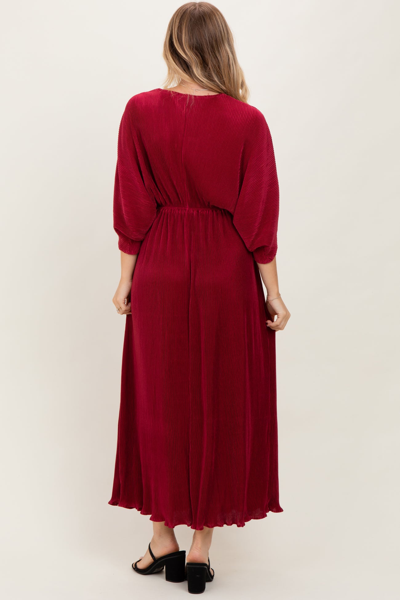 woman wearing a long burgundy maxi dress with a cinched waist and balloon sleeves, viewed from the back