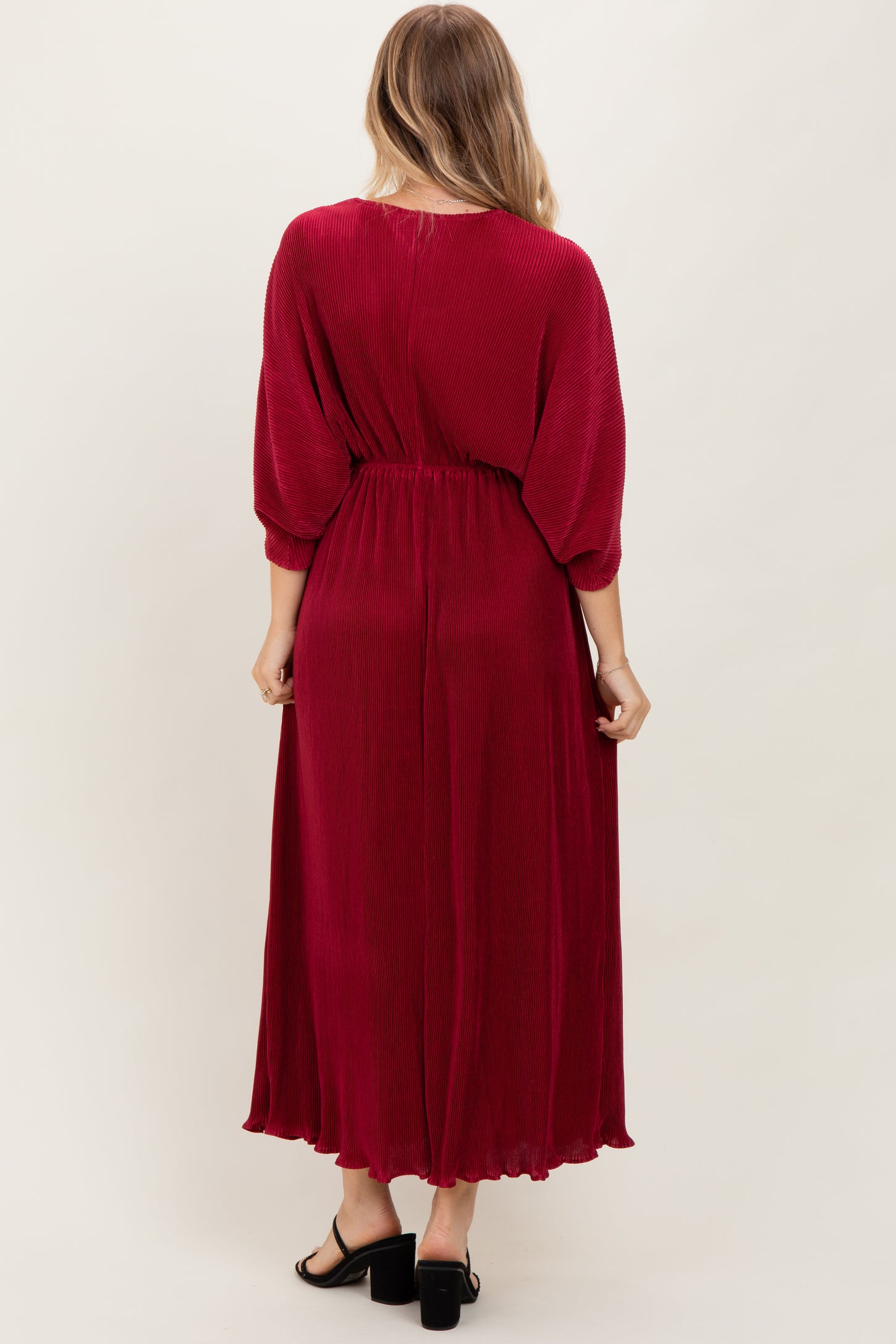 woman wearing a long burgundy maxi dress with a cinched waist and balloon sleeves, viewed from the back
