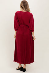 woman wearing a long burgundy maxi dress with a cinched waist and balloon sleeves, viewed from the back