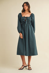 woman wearing a dark teal long sleeve smocked midi dress with a square neckline and puffed sleeves