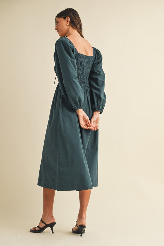 woman wearing a dark green puff sleeve midi dress with a smocked back and square neckline