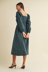 woman wearing a dark green puff sleeve midi dress with a smocked back and square neckline