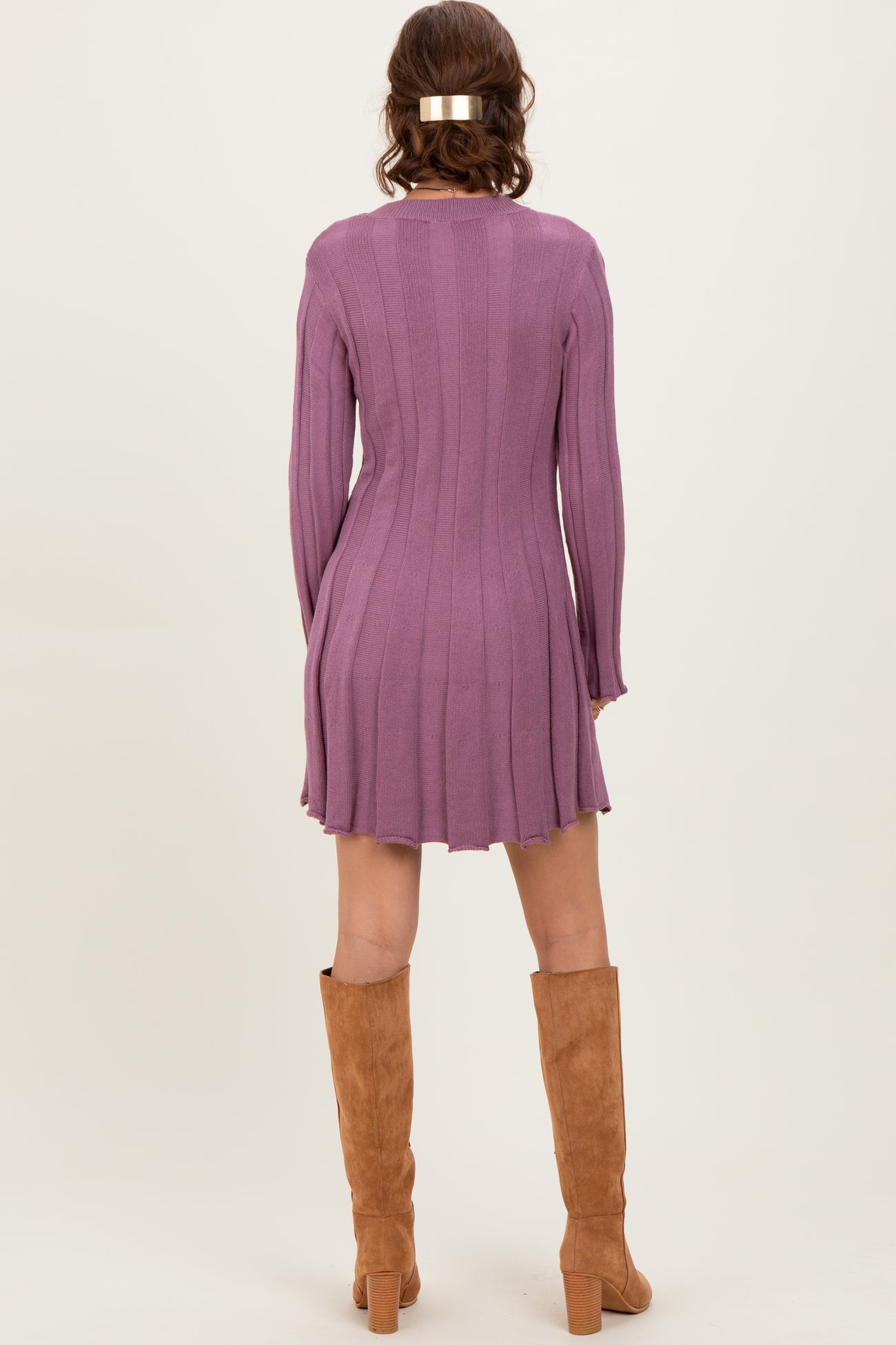 woman wearing a ribbed purple long sleeve sweater dress with a flared hem and tan knee-high boots